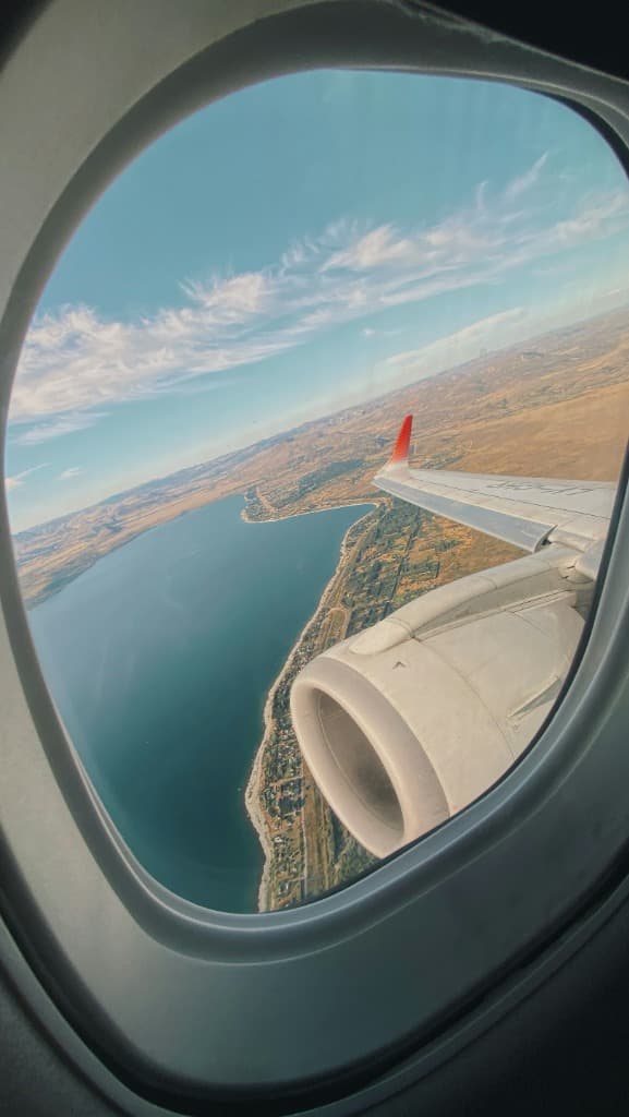 Airplane window view overlooking coast and wings